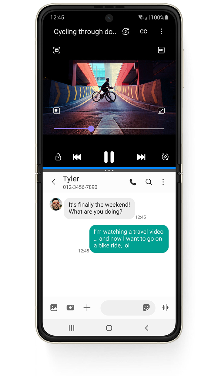 Galaxy Z Flip3 5G unfolded in Multi Active Window, with a YouTube video on top, a video called Cycling Through Downtown and a person standing on a bike on a ramp. The Messages app on the bottom and the received text message from Tyler says "It's finally the weekend! What are you doing?". The sent text message says "I'm watching a travel video... and now I want to go on a bike ride, lol"